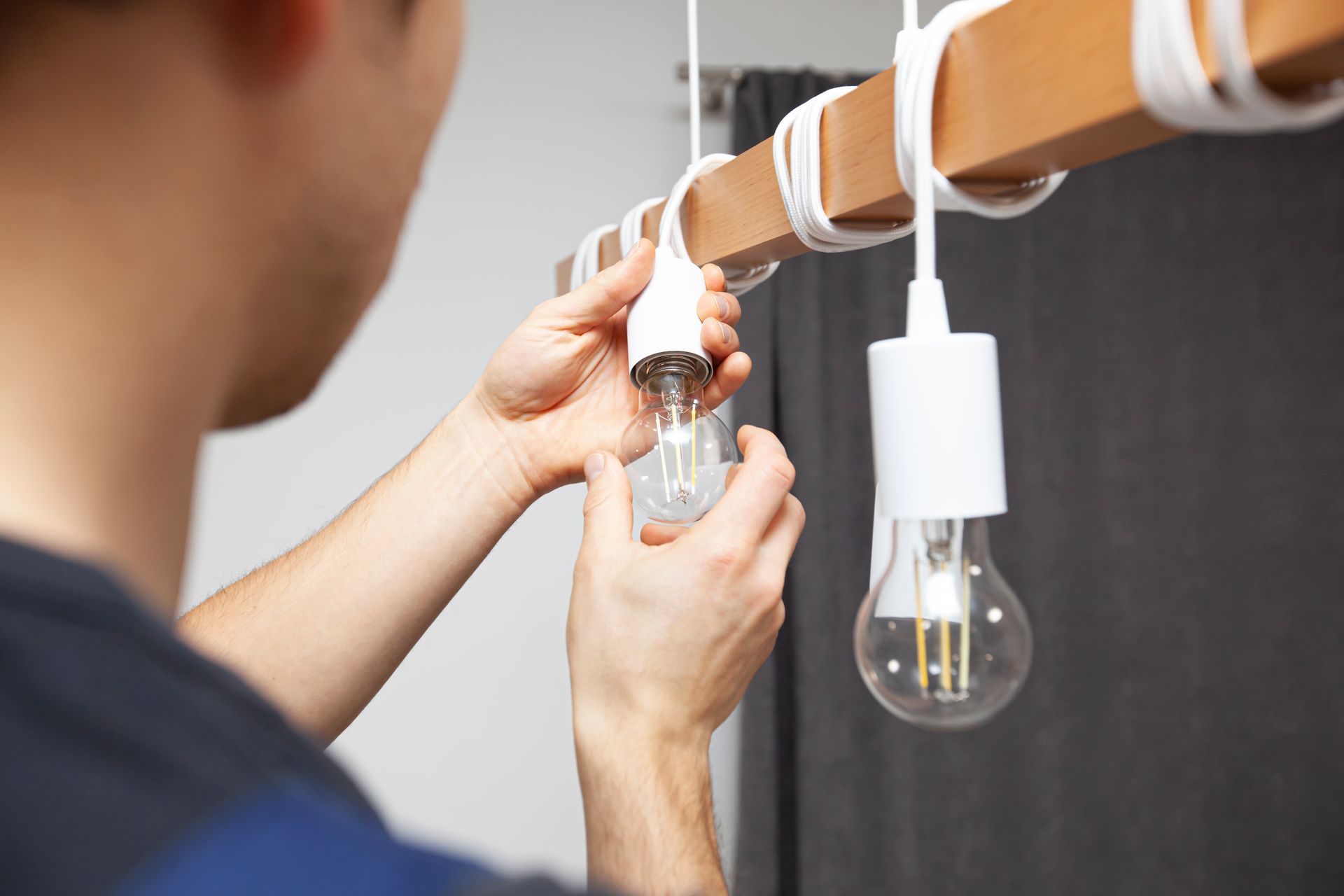 electrician is installing led light bulbs into chandelier