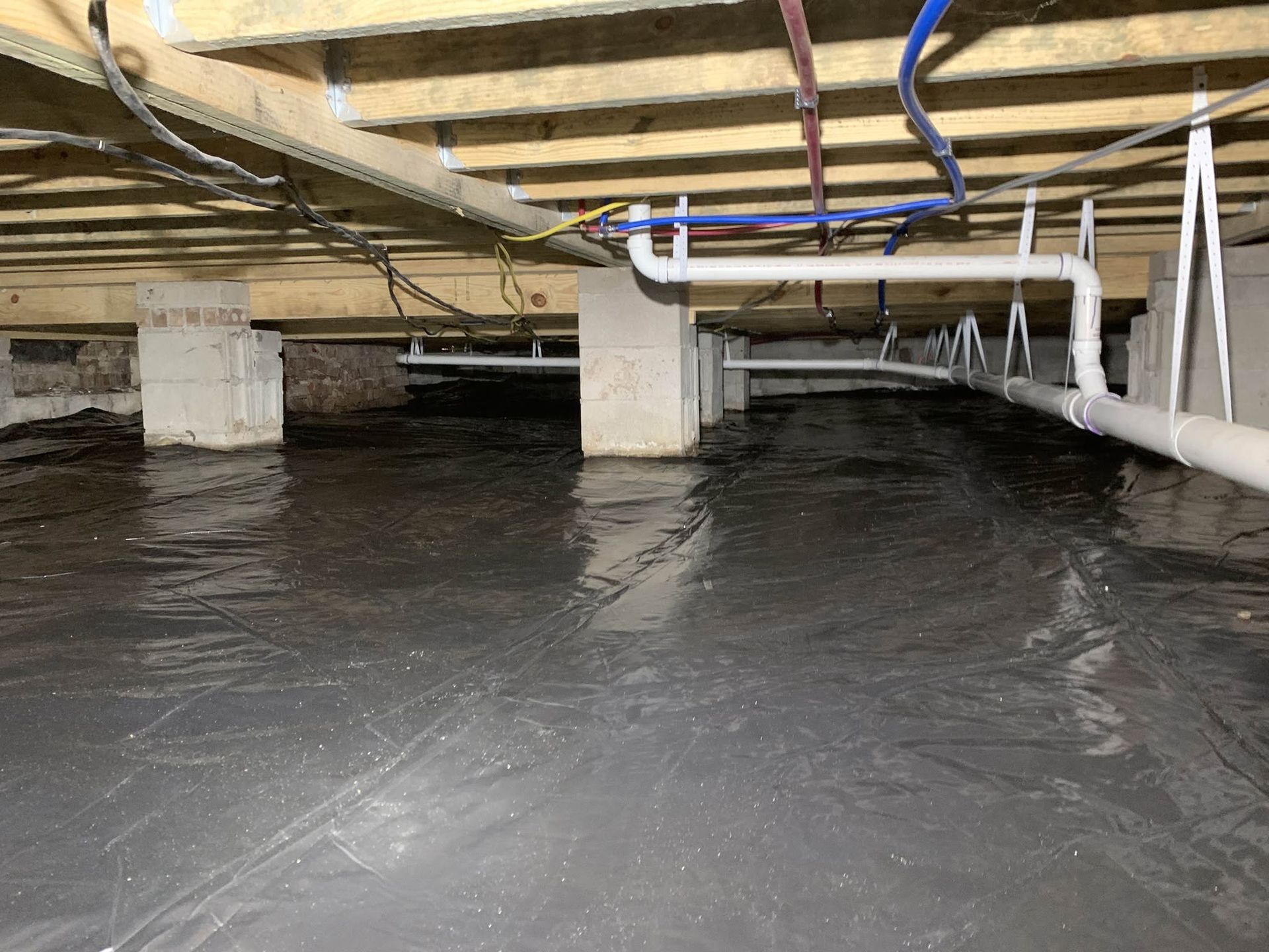 Underneath a raised wooden structure with concrete supports and black water below