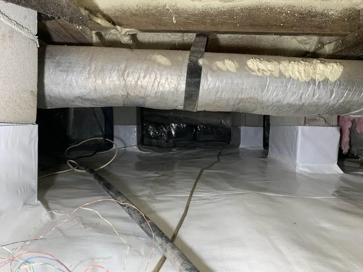 Insulated ducts and pipes under a low crawlspace or attic floor with plastic sheeting on the ground