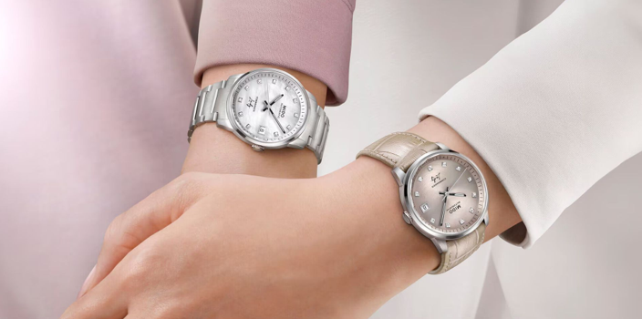 Due polsi con orologi d'argento su maniche rosa tenue e beige