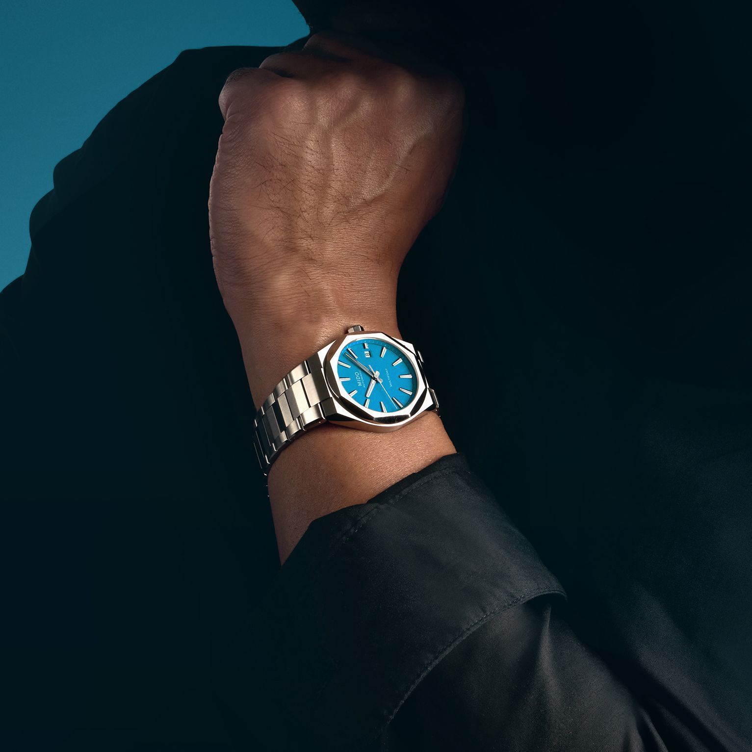 Primo piano di un polso con un orologio d'argento dal quadrante blu su una manica scura