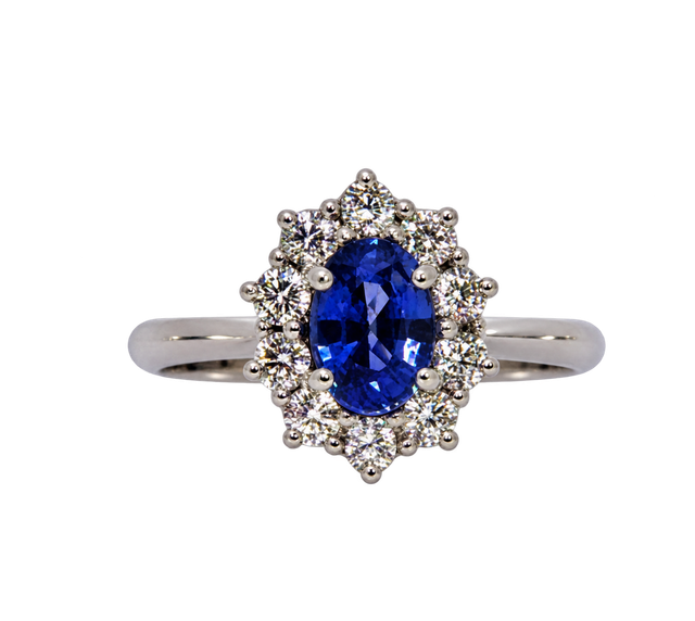 Anello in argento con gemma ovale blu circondata da piccole pietre trasparenti.