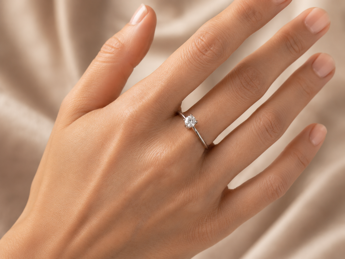 Mano con anello di fidanzamento con diamante su sfondo beige