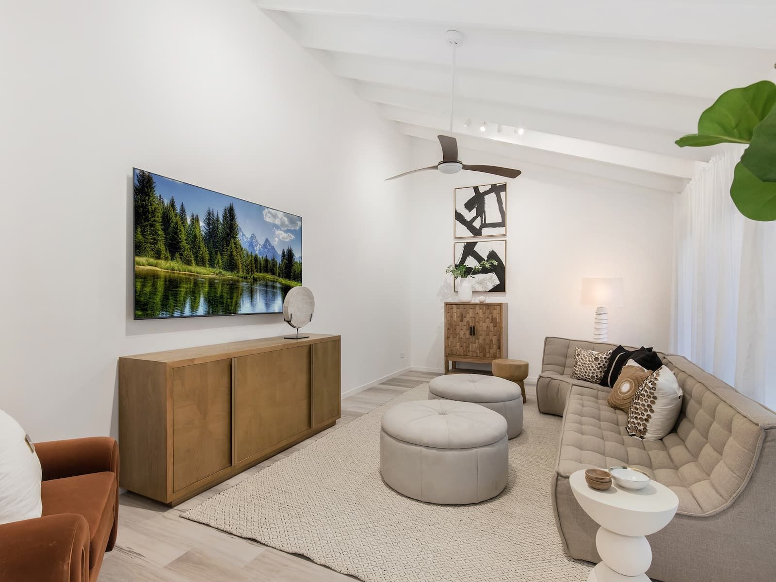 Living room with beige sofa, wooden cabinet, TV, and light-colored rug.