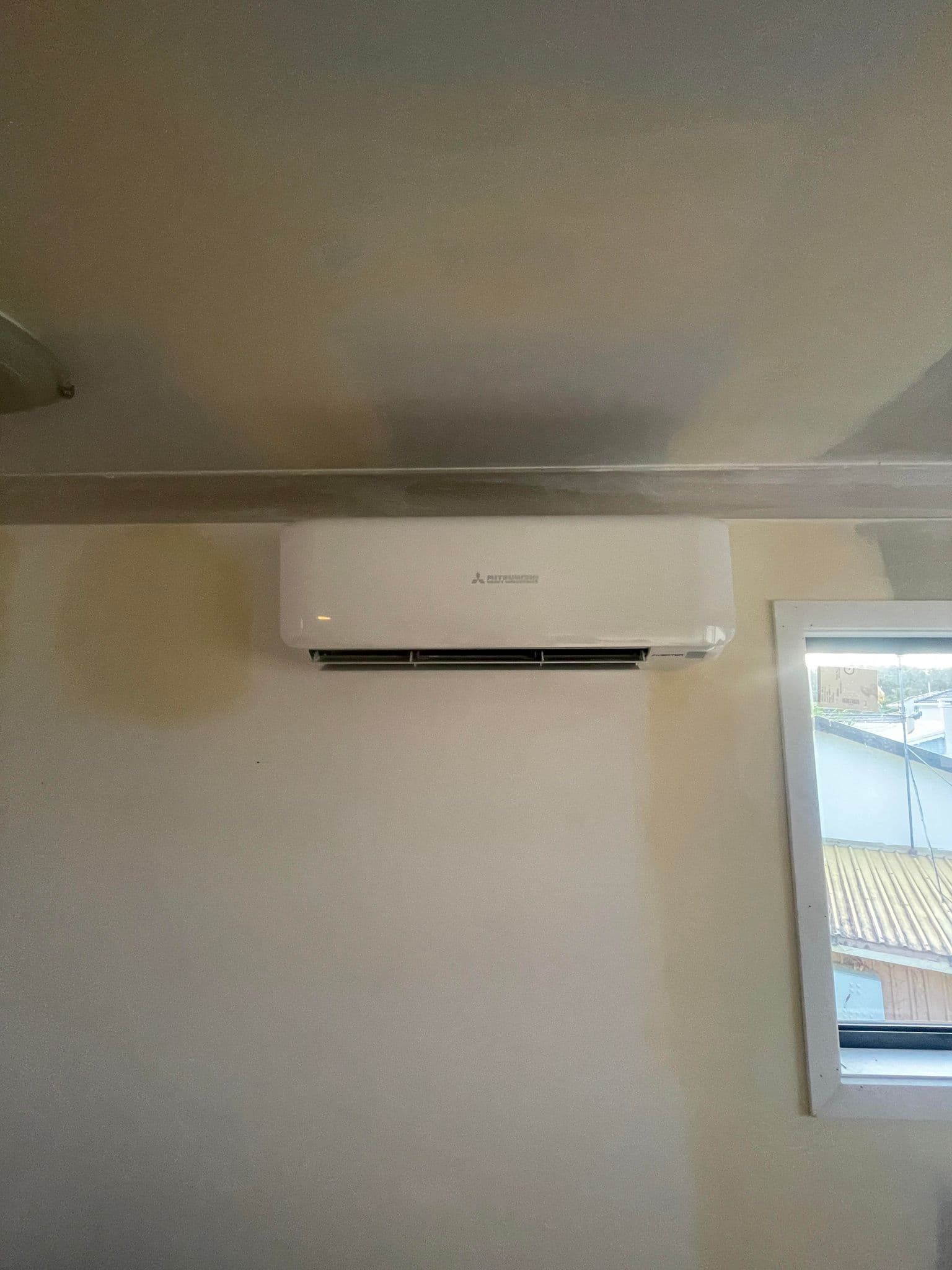 a room with a window and a wall mounted air conditioner .