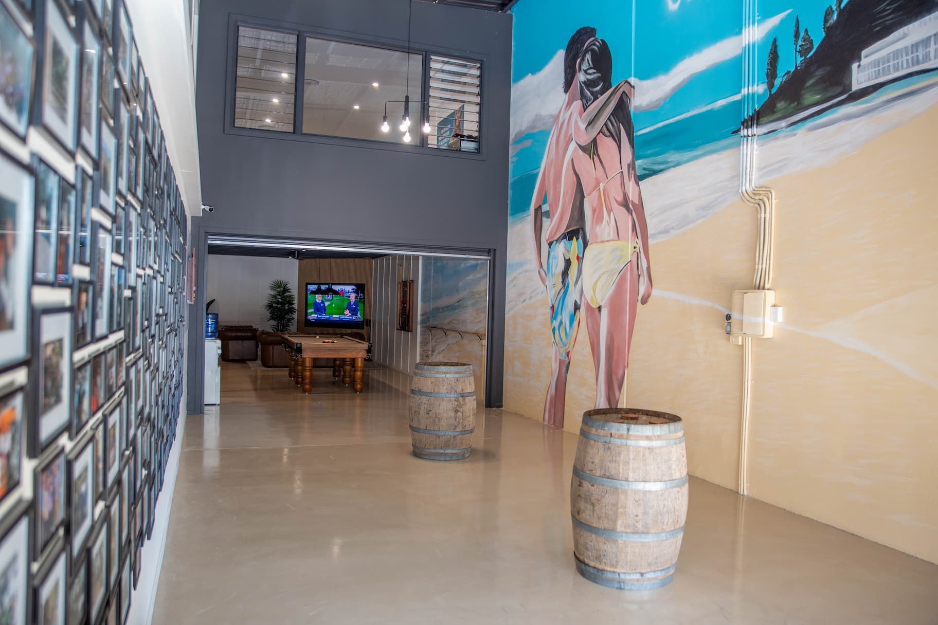 Hallway with mural, framed photos, and barrels. A television is visible in the background.
