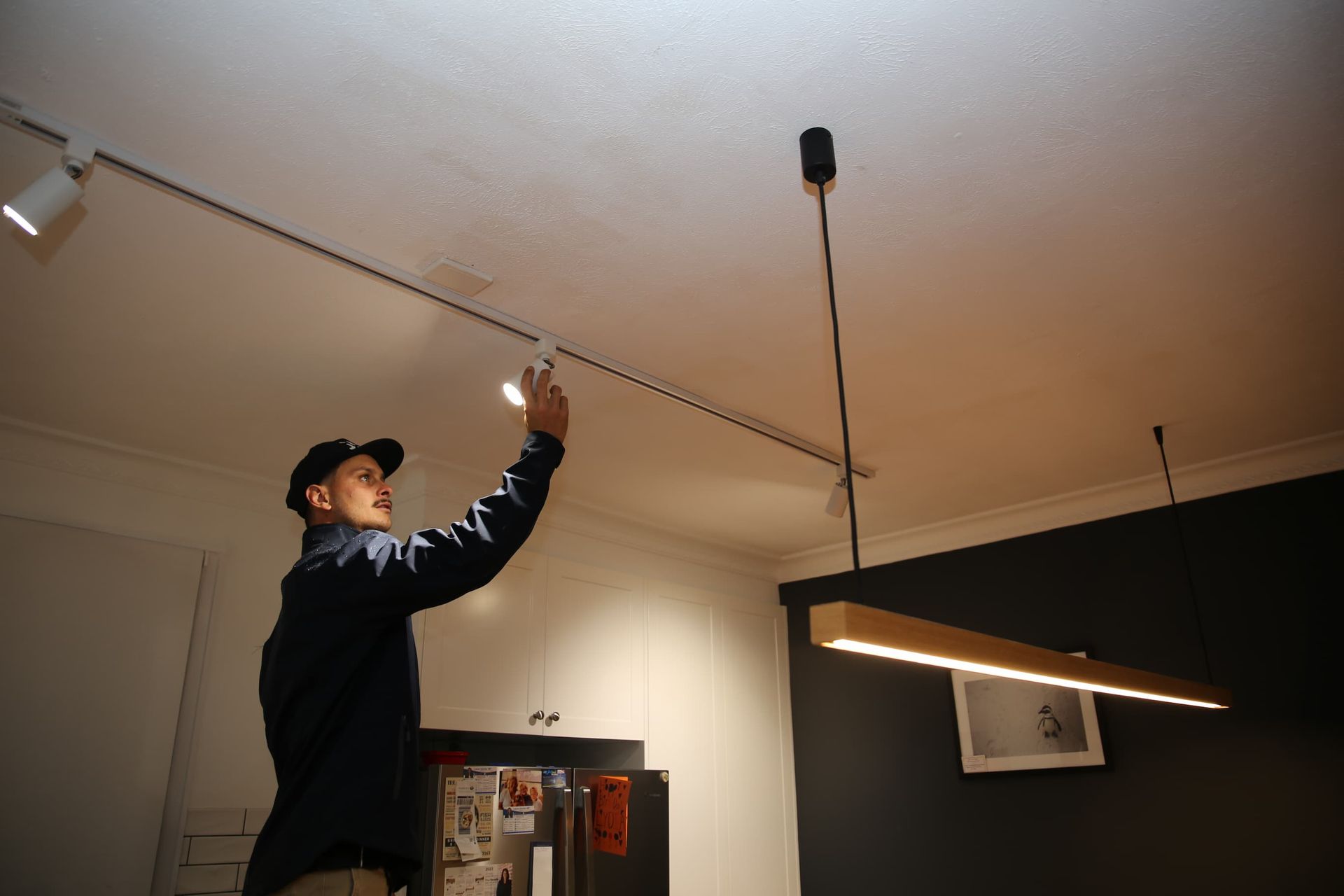 a man adjusts a light on a track in a kitchen