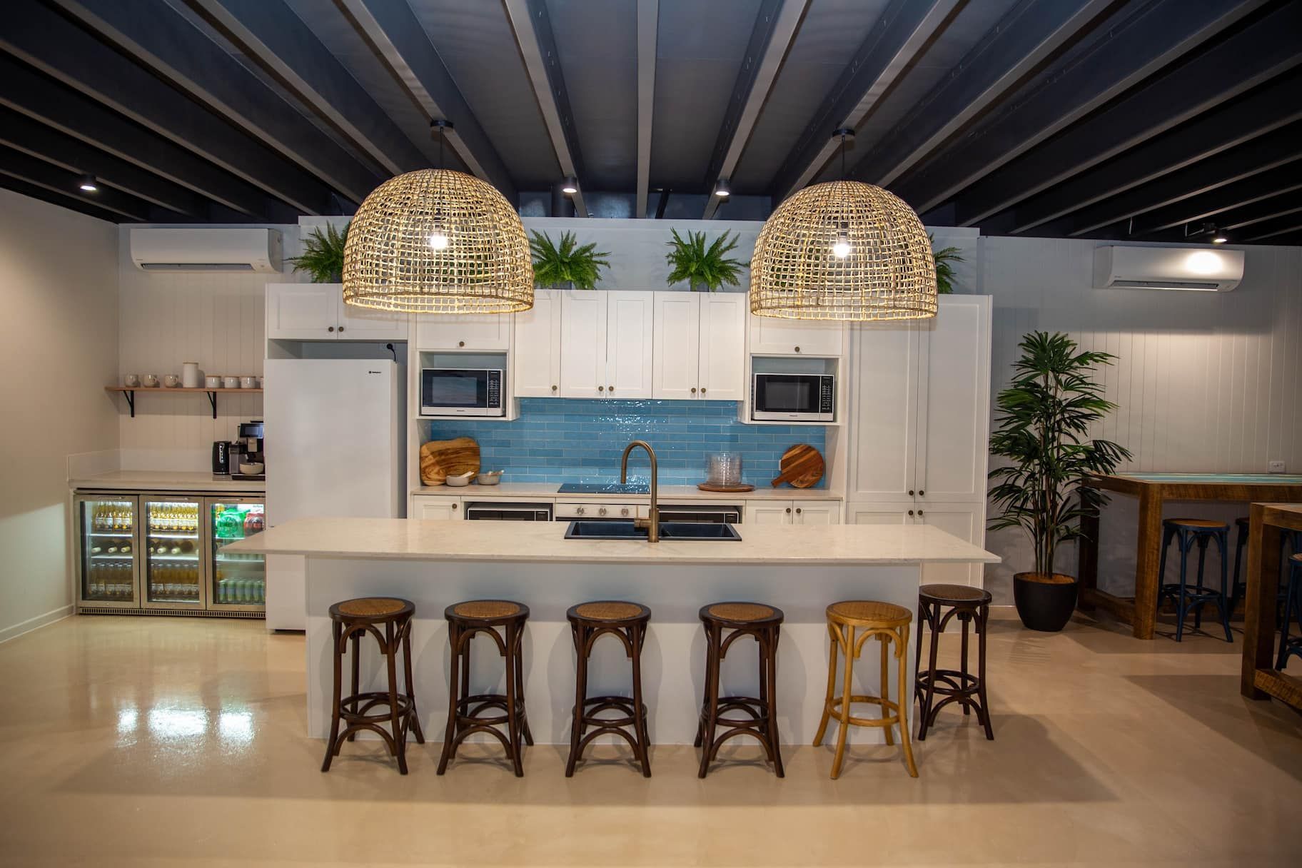 Modern kitchen with white cabinets, island seating, and woven pendant lights.