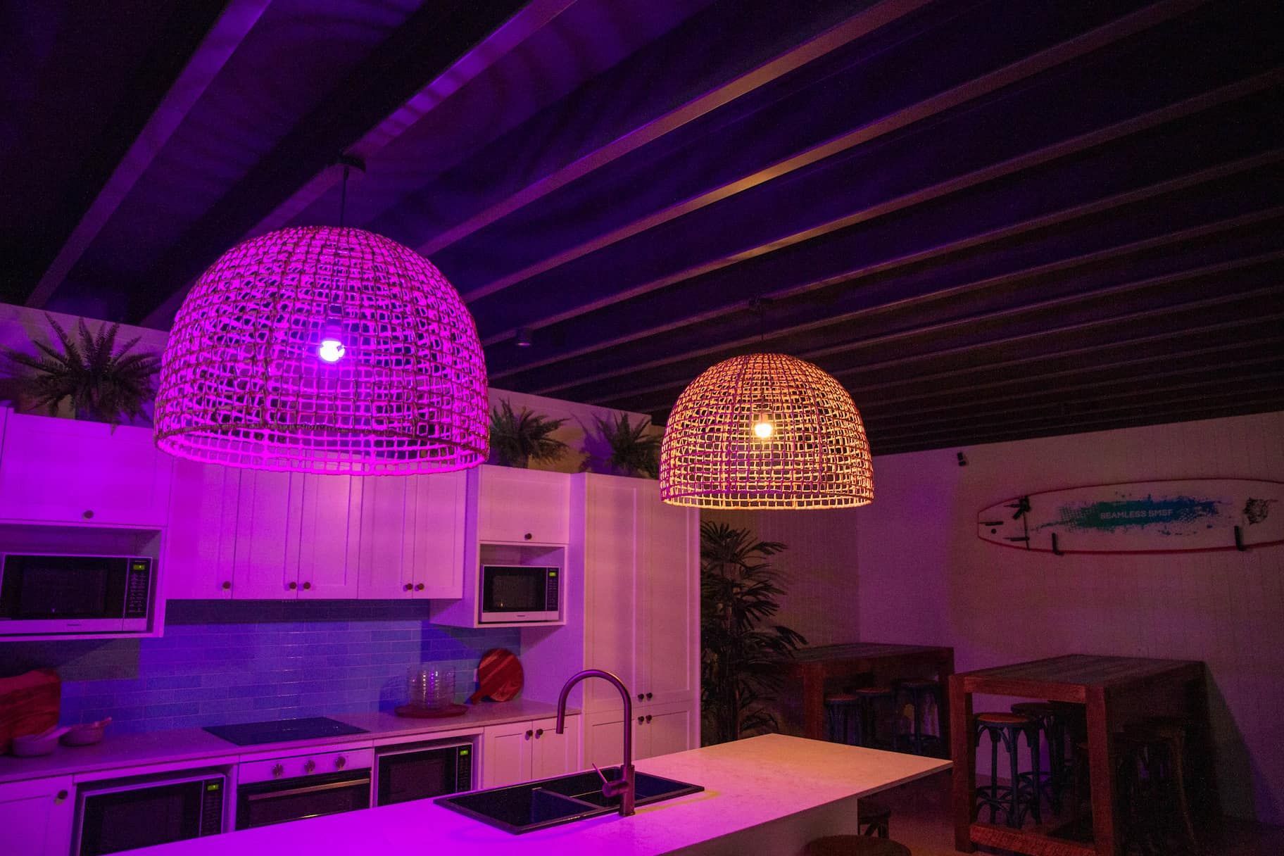 Kitchen with pink and orange woven lamps, white cabinets, and blue tile backsplash.