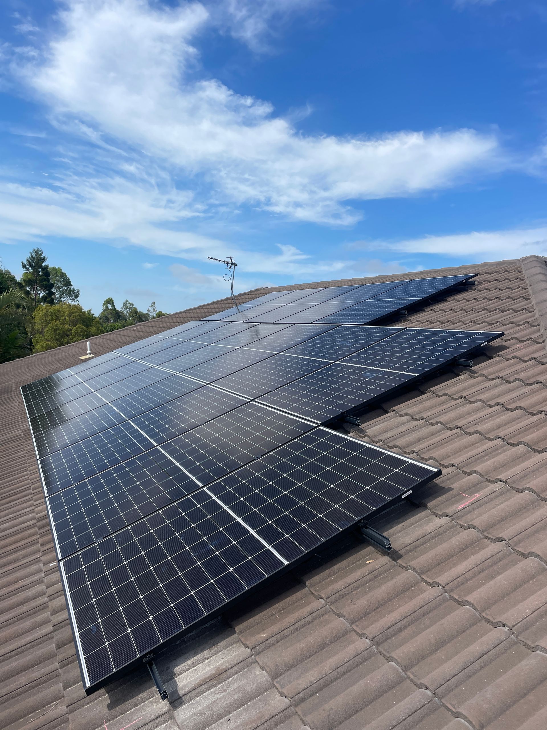 A row of solar panels sitting on top of a tiled roof.