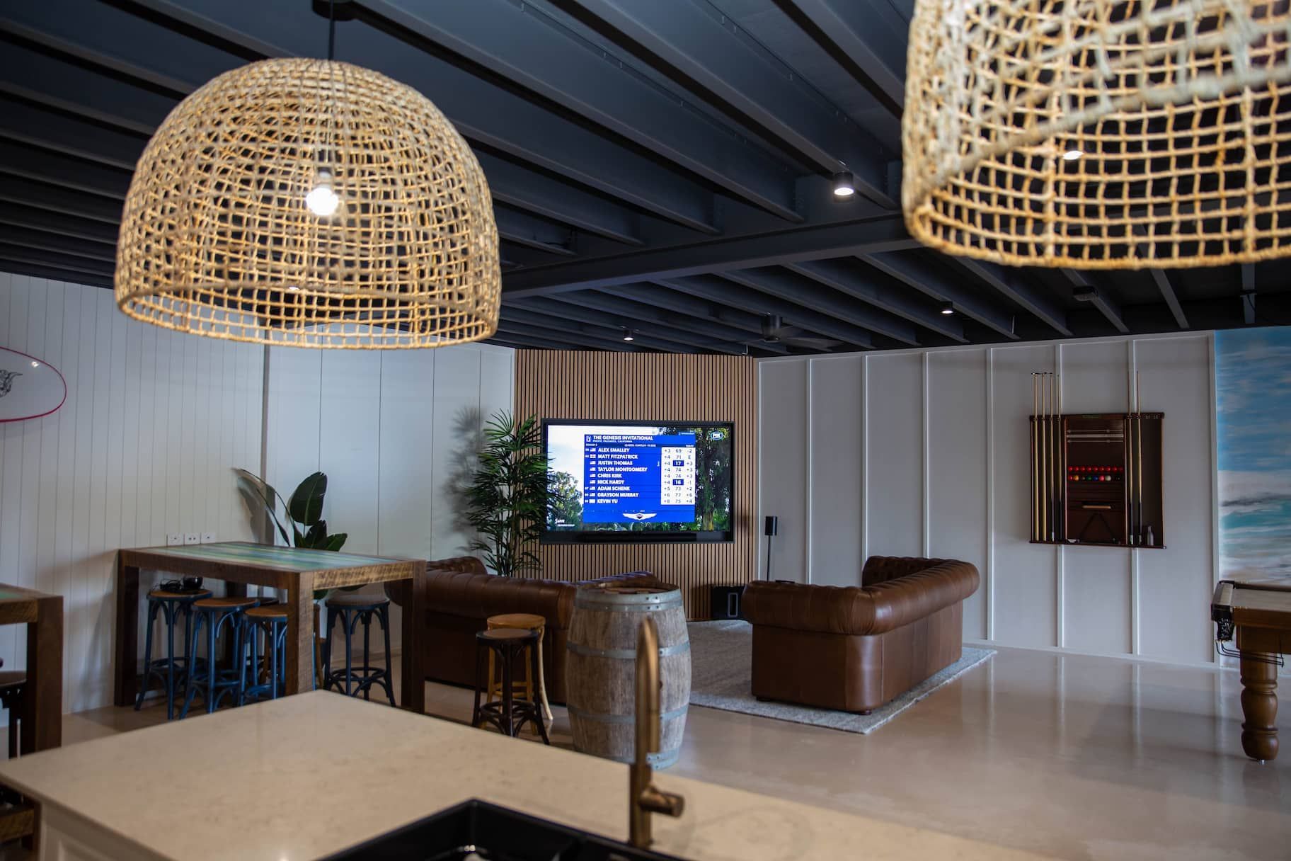 Living room with brown leather sofas, TV, and woven pendant lights.