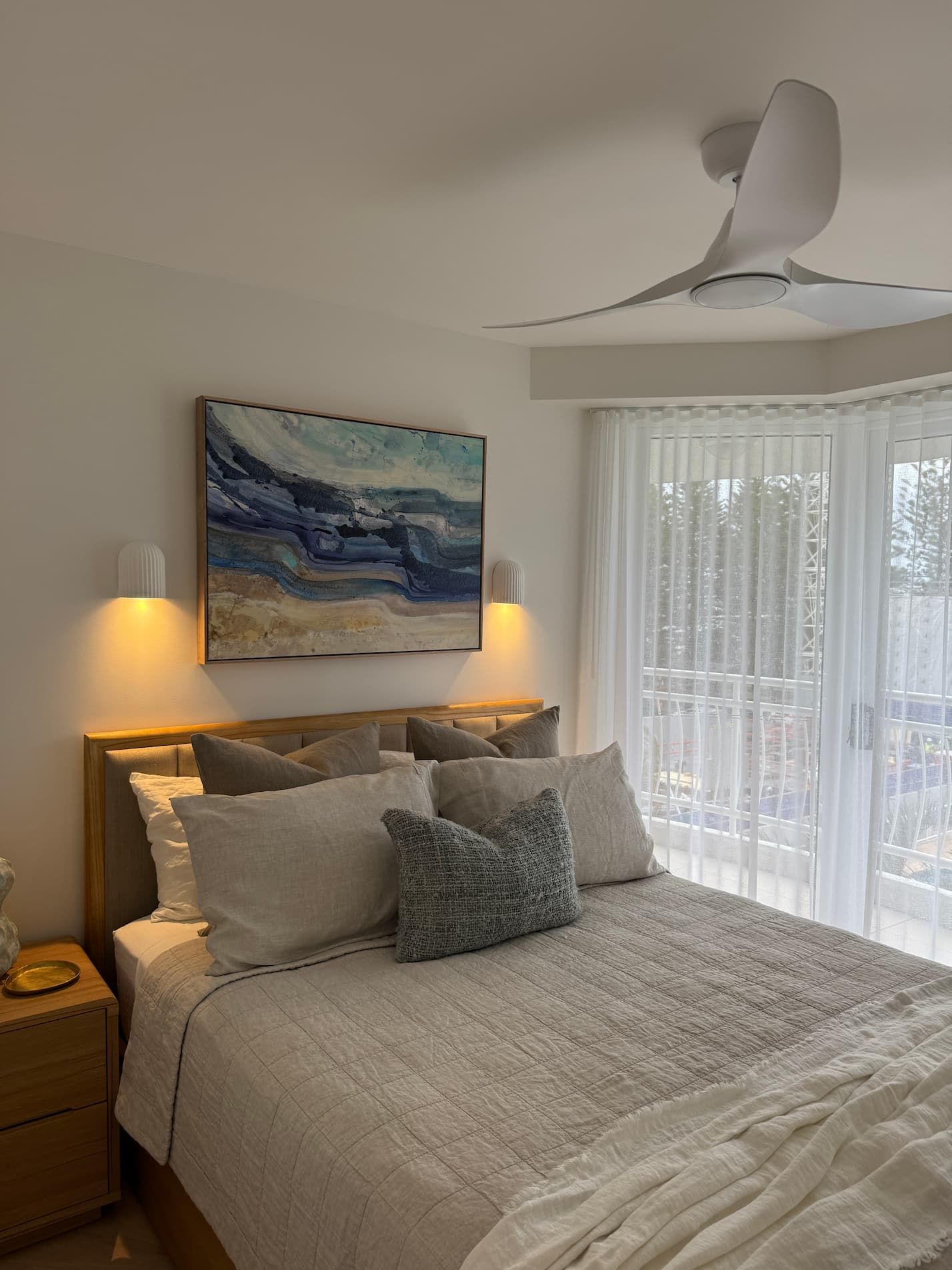 Bedroom with a bed, artwork, and a ceiling fan. Neutral colors, light and airy.