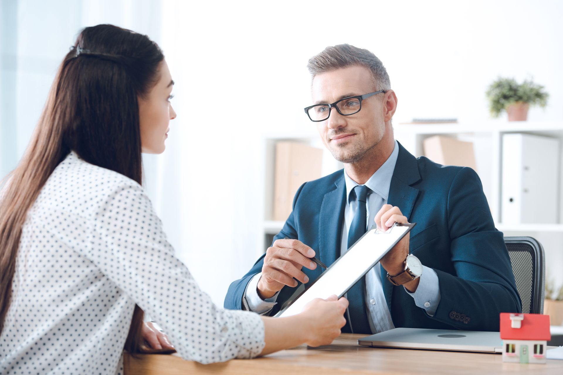 An insurance agent in a suit reviewing a policy document with a business owner