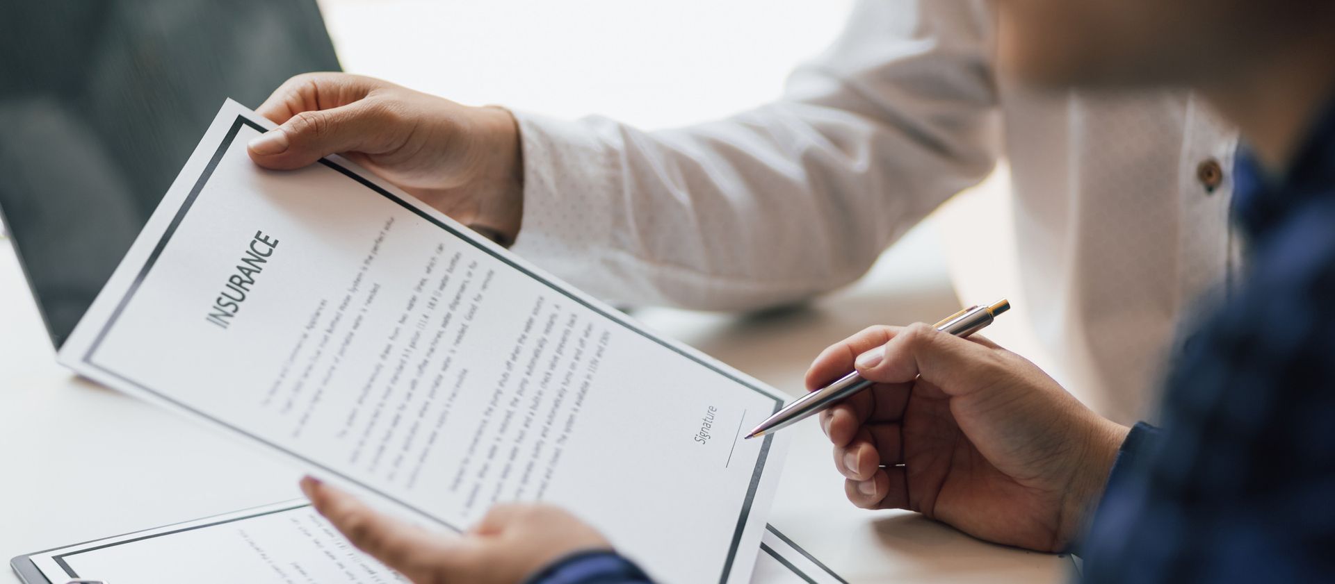 Close-up of an agent from a local insurance agency, reviewing an insurance policy with their client.