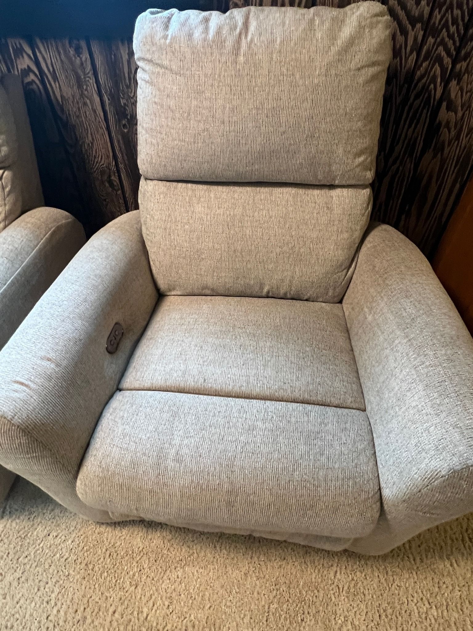 A recliner is sitting on a carpet in a living room next to a couch.