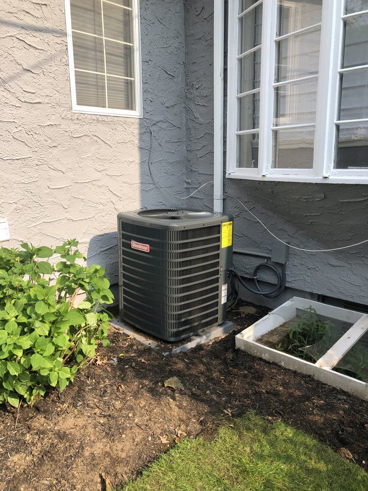 an air conditioner is sitting on the side of a house next to a window .