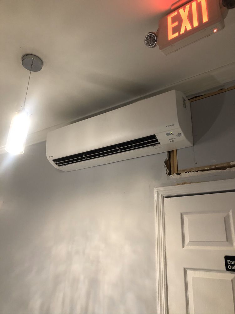 an air conditioner is hanging from the ceiling next to an exit sign .