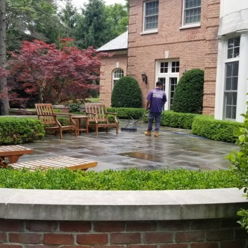 Man cleaning a stone patio.
