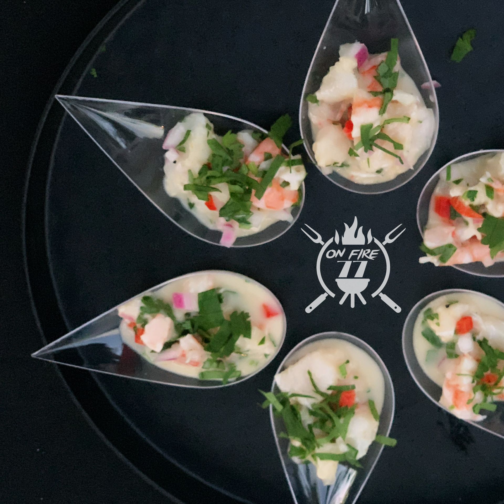 Six small leaf-shaped bowls of salad on a black tray with a white logo center