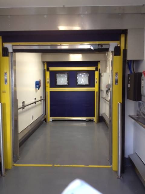 Yellow and blue industrial door, open in a hallway.