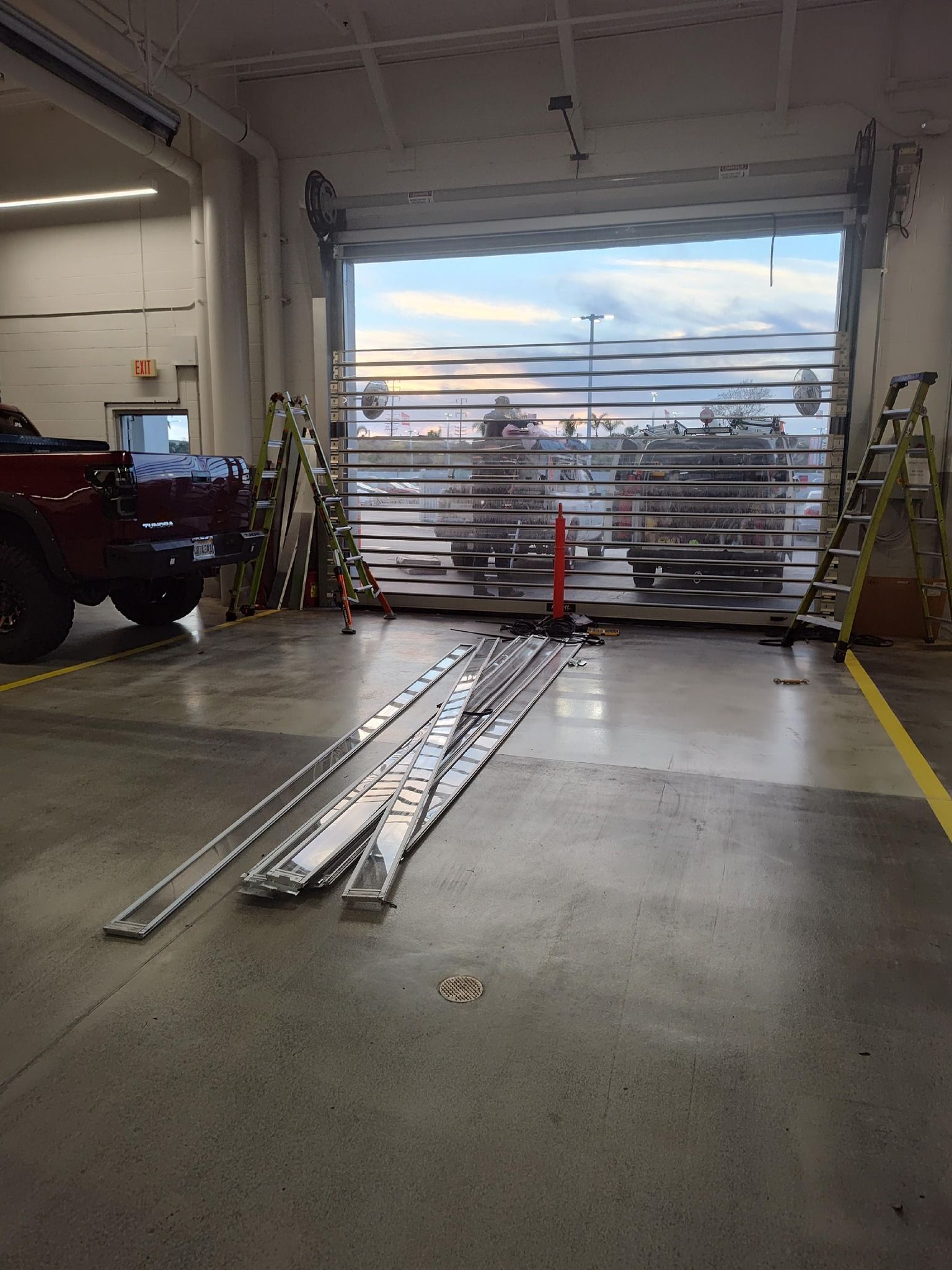 A red truck is parked in a garage with a garage door open.