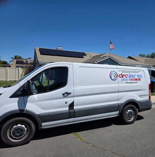 White service van parked on a street, with company logo on the side and a solar-paneled roof in the background