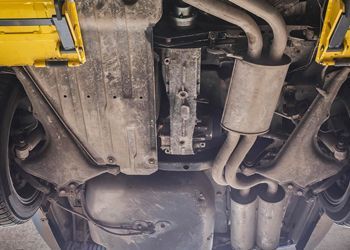 A close up of the underside of a car with exhaust pipes.