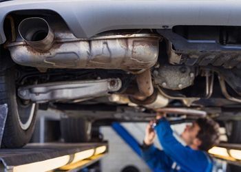 A man is working on the underside of a car in a garage.