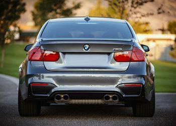 The back of a bmw m3 is parked on the side of the road.