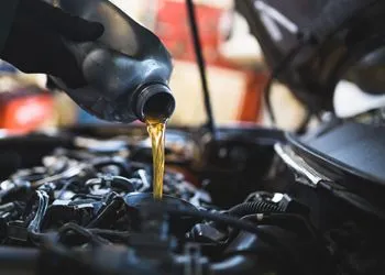 A person is pouring oil into a car engine.