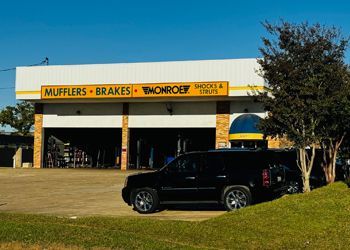 A black suv is parked in front of a monroe auto repair shop.