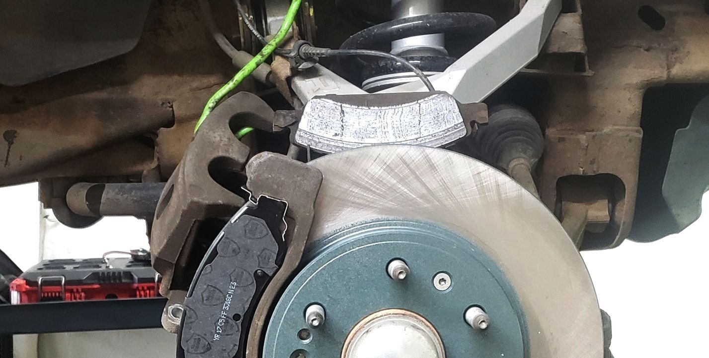 Car brake assembly with a rotor, caliper, and brake pads.