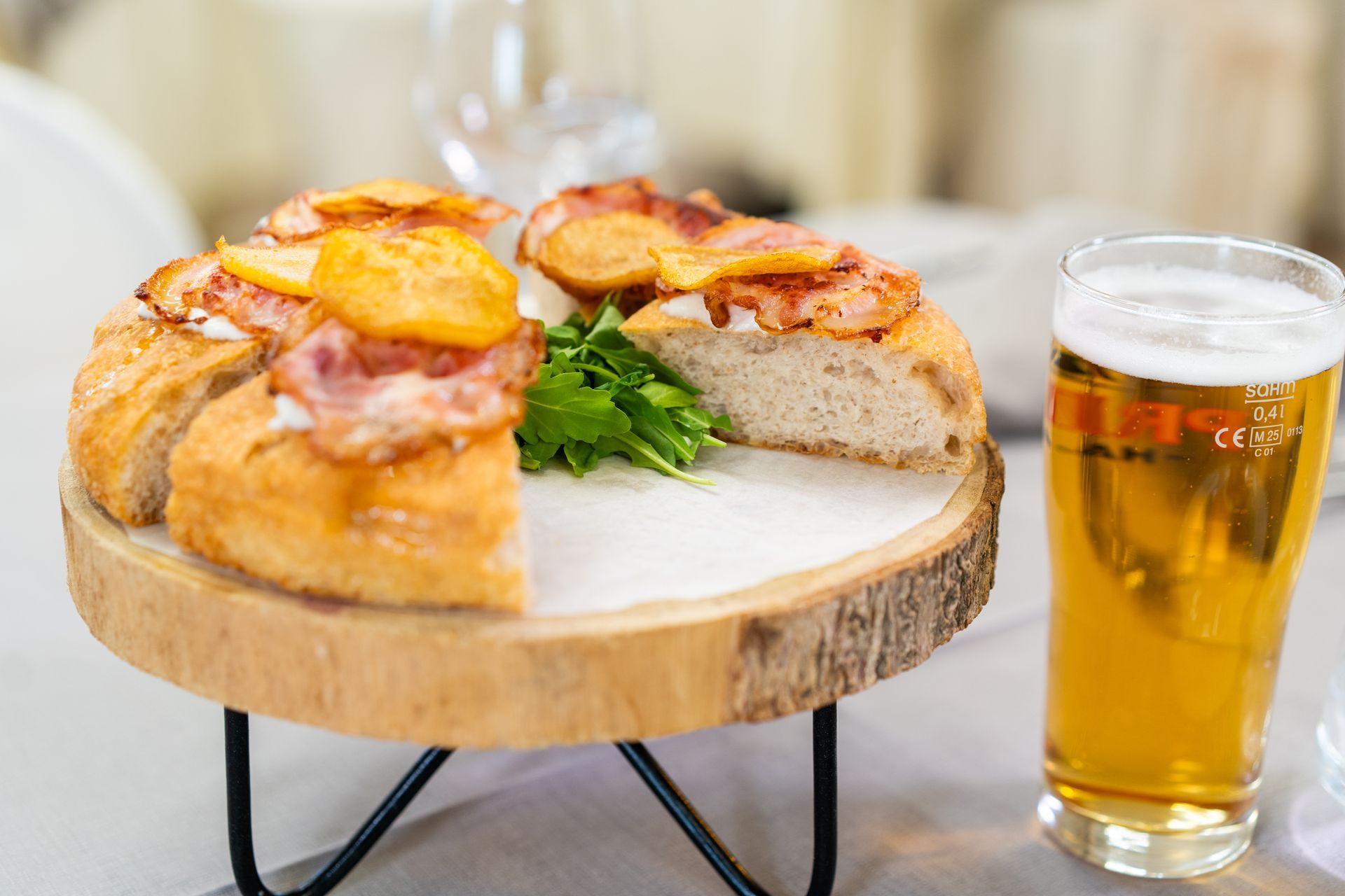 Pizza con prosciutto, formaggio e cipolla caramellata, guarnito con foglie verdi.