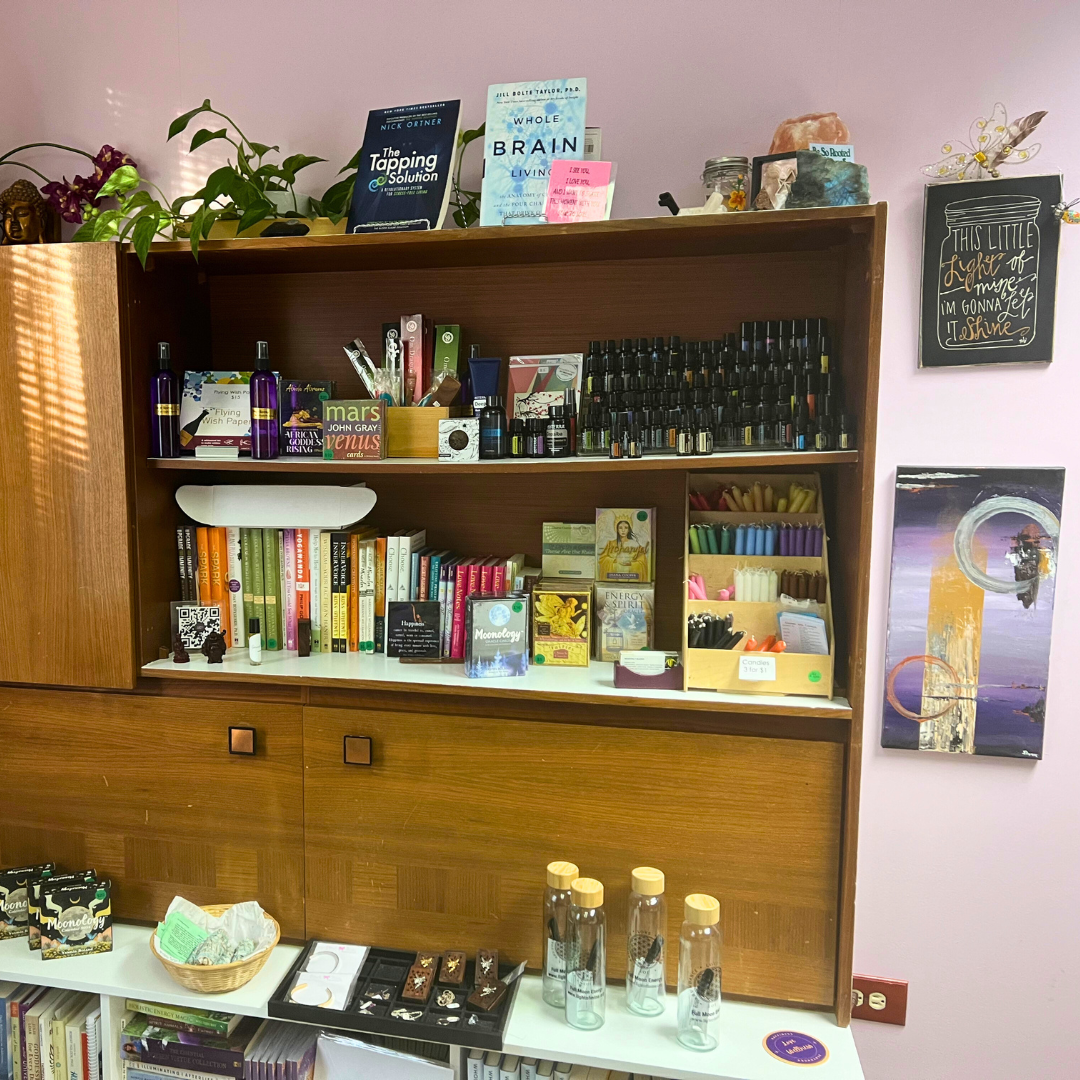 Dena Gould's bookcase with essential oils, oracle cards, and other metaphysical healing tools in her Denver healing office