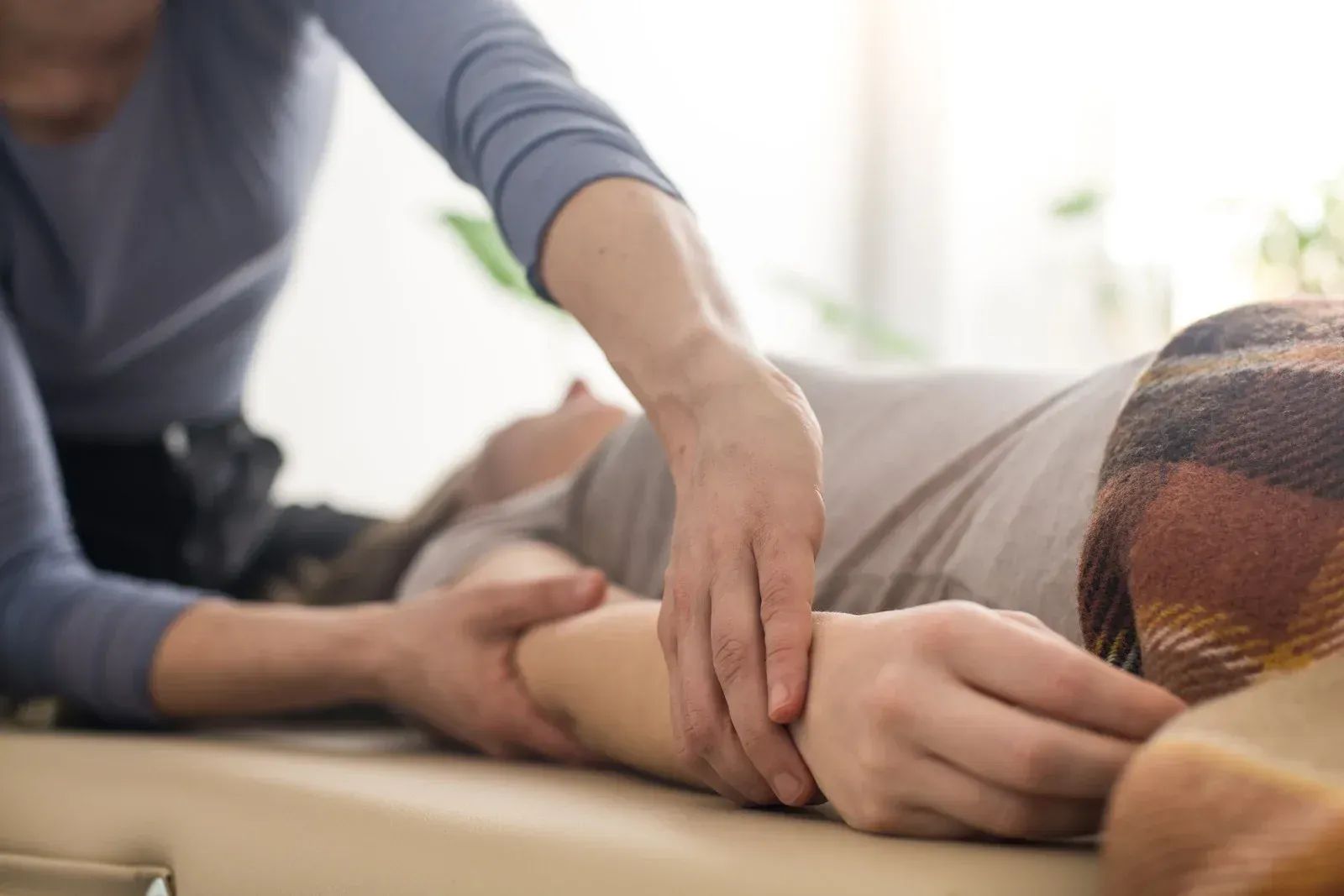 Hands gently holding a resting person's arm in a bright indoor setting