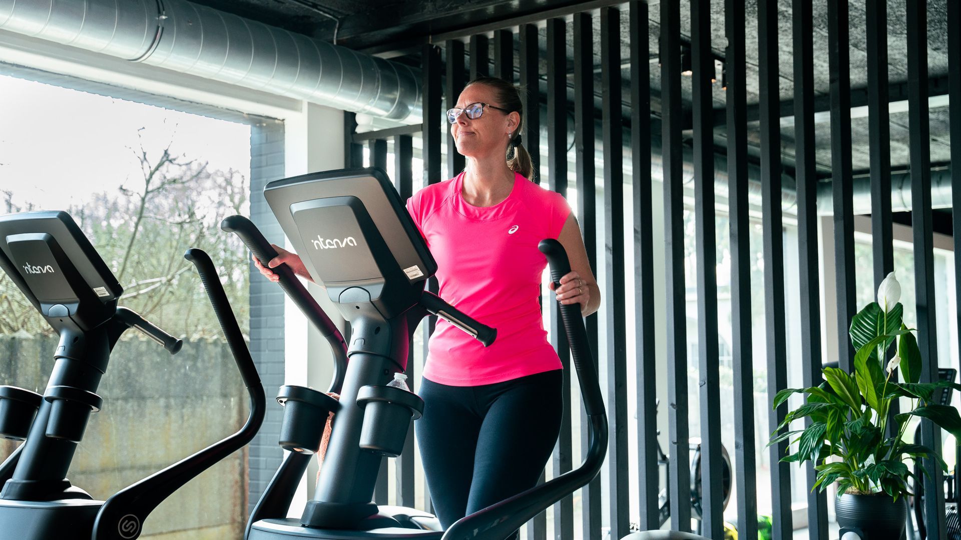Een vrouw rijdt op een crosstrainer in een sportschool.