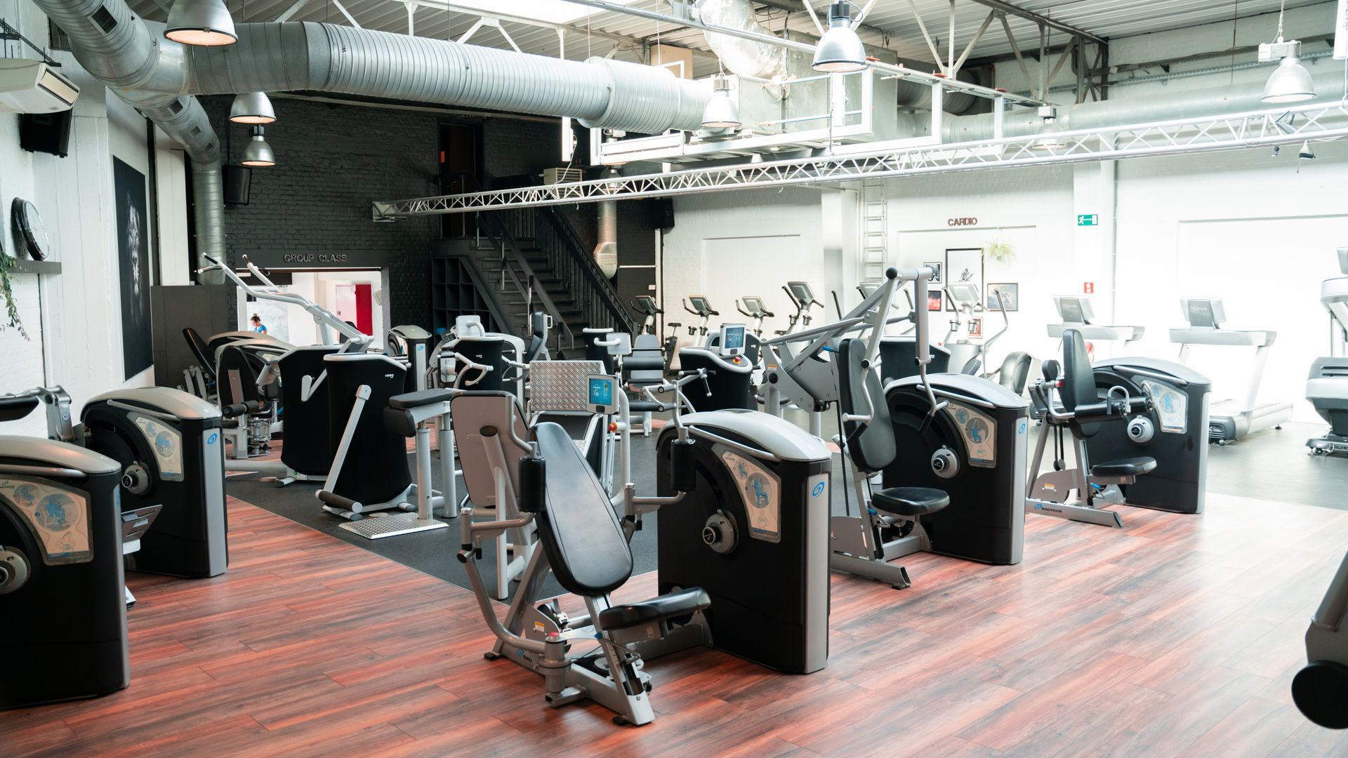 Een sportschool vol met fitnessapparatuur en een houten vloer.
