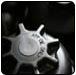 Close-up of a silver gear with multiple points, possibly part of a machine or mechanism.  |  Quality Car & Truck Repair Inc