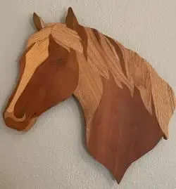 Wooden horse head sculpture in shades of brown, mounted on a wall.