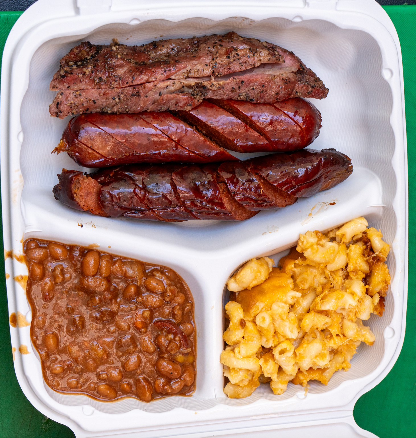 A plastic container filled with meat beans and macaroni and cheese