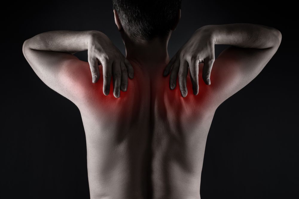 A man is holding his shoulder in pain.
