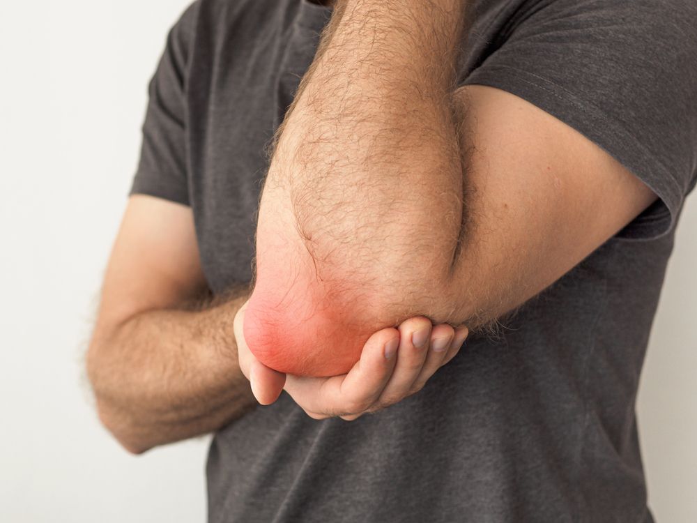 A man is holding his elbow in pain.