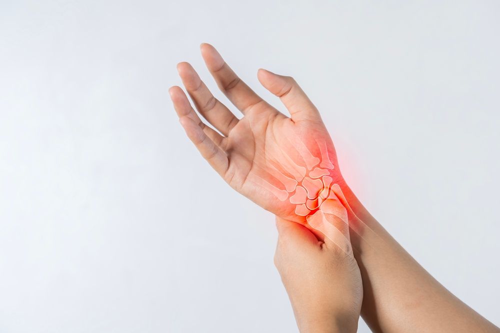 A person is holding their wrist in pain.