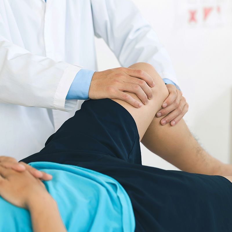 A doctor is examining a patient 's leg and knee