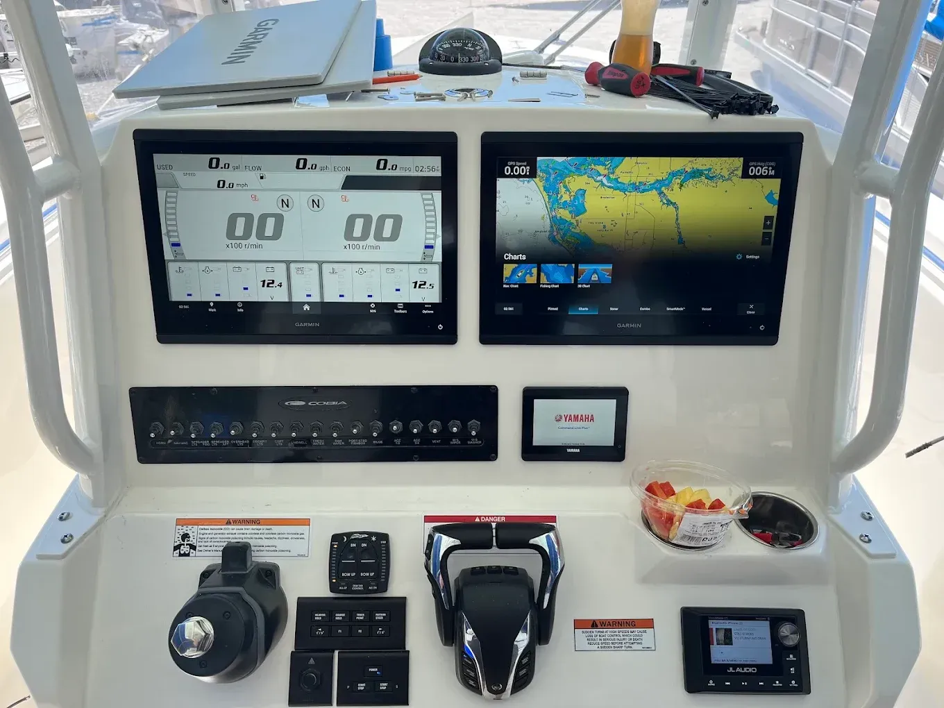 Boat helm dashboard with digital gauges, GPS display, and steering controls in a white console