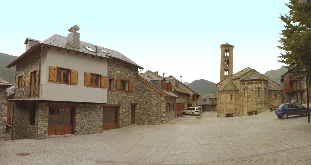 Edificis de pedra i una església amb campanar en una plaça empedrada.