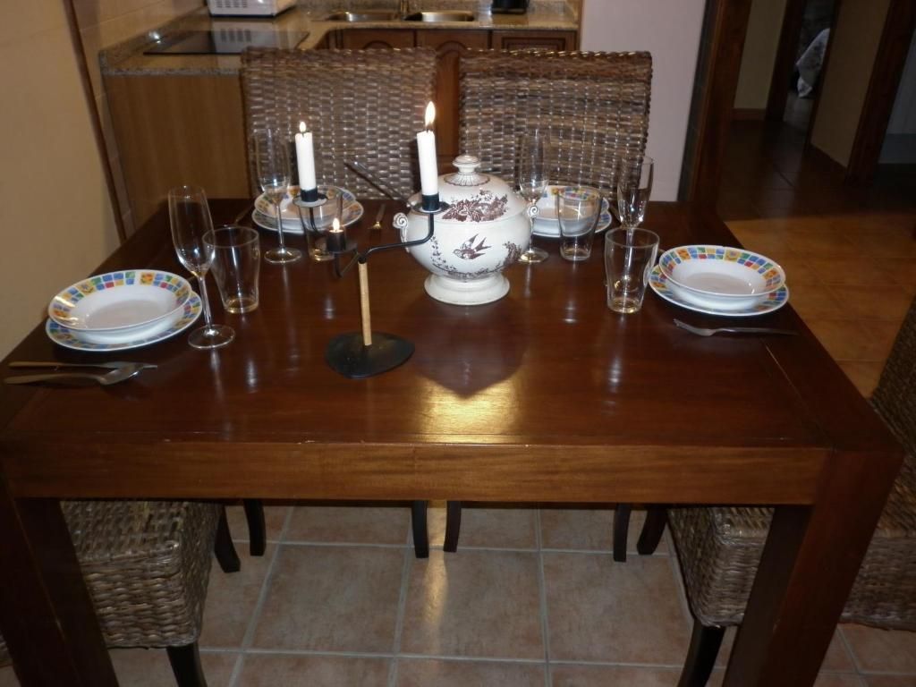 Taula de menjador parada per a un àpat, amb plats, gots i espelmes, en una cuina.