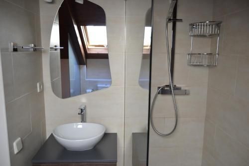 Bany amb lavabo blanc, mirall gran i dutxa amb accessoris platejats.