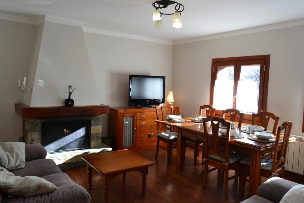 Sala d'estar amb llar de foc, televisor, taula de menjador i mobles de fusta marró.