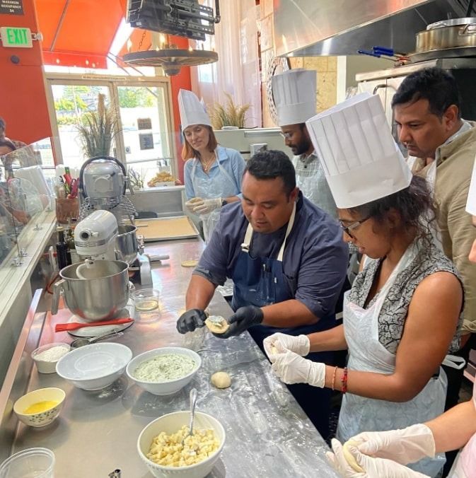 People making dumplings in a bright kitchen, with bowls of filling, flour, and a stand mixer nearby